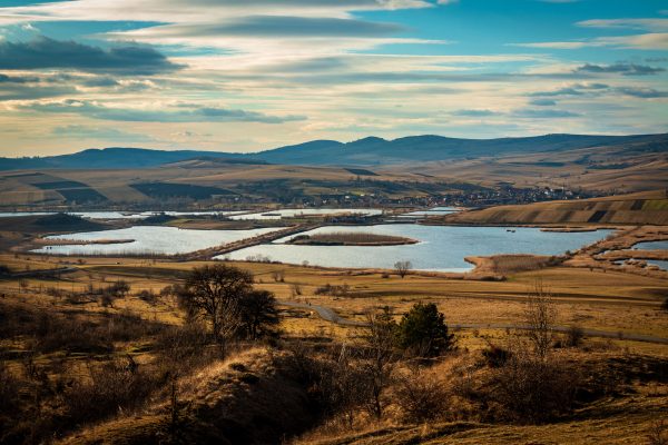 A breathtaking aerial view of a serene rural landscape with fish ponds and rolling hills under a dynamic sky. Nature 4K