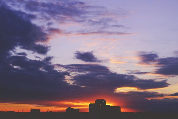 A breathtaking sunset casting vibrant hues over a city skyline, featuring dramatic clouds. Nature 4K
