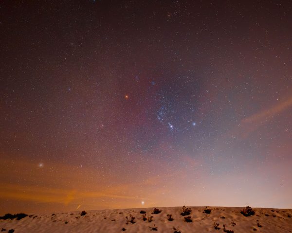A breathtaking view of Orion's Belt in the starry night sky over a serene desert landscape. Espace 4K