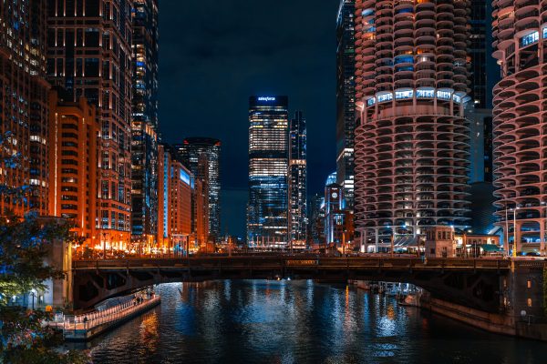 A captivating night view of the Chicago River flanked by towering skyscrapers and illuminated city lights. Architecture 4K