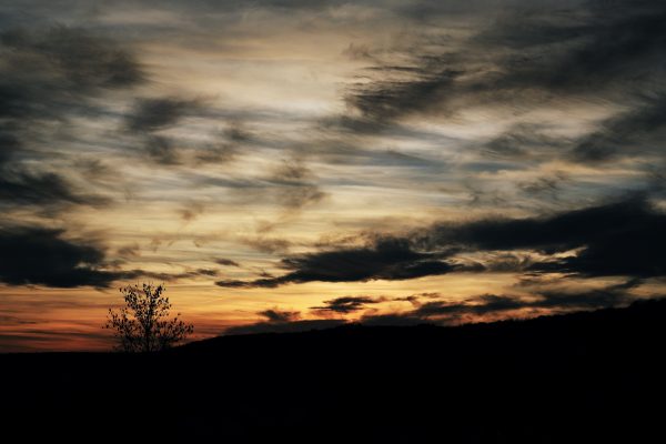 A captivating sunset with dramatic clouds over a silhouetted landscape. Dark 4K