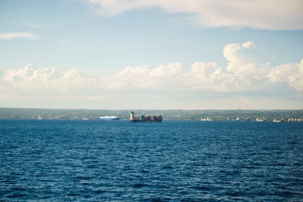 A cargo ship sails on the ocean with a scenic horizon and bright clouds in the sky. Nature 4K
