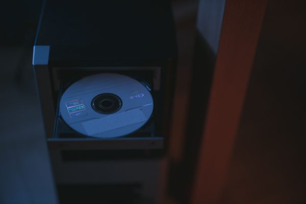 A close-up image of a CD partially ejected from a drive, showcasing soft lighting. Voitures 4K
