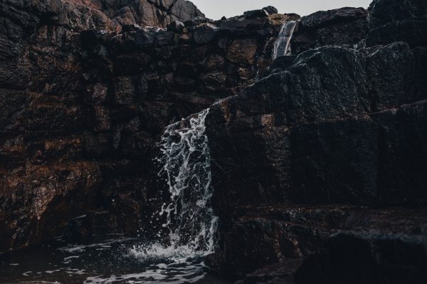 A close-up of a cascading waterfall over dark geological rock formations. Nature 4K