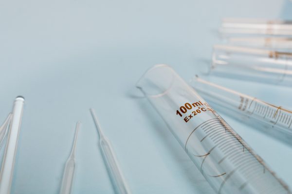A collection of transparent glass test tubes on a soft blue surface, ideal for scientific research visuals. IA Générative 4K