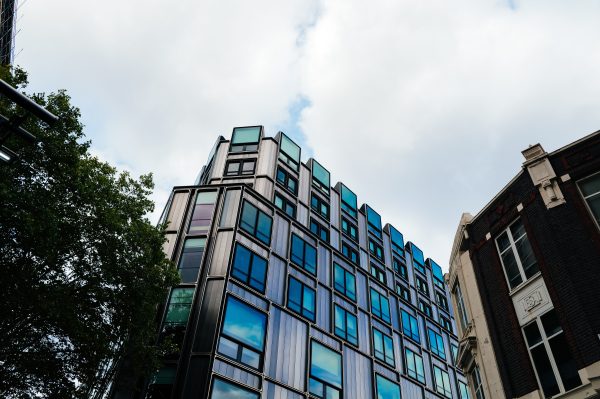 A contemporary building with reflective windows in an urban setting under a cloudy sky. Architecture 4K