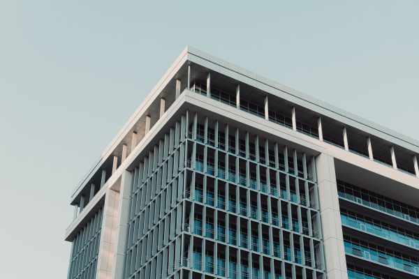 A contemporary high-rise building with a glass facade set against a clear sky. Architecture 4K