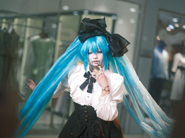 A cosplayer in a detailed anime costume poses confidently in an indoor setting, showcasing vibrant colors and style. Manga 4K
