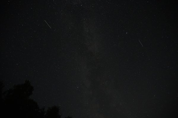 A dark night sky filled with stars and visible shooting stars. Espace 4K