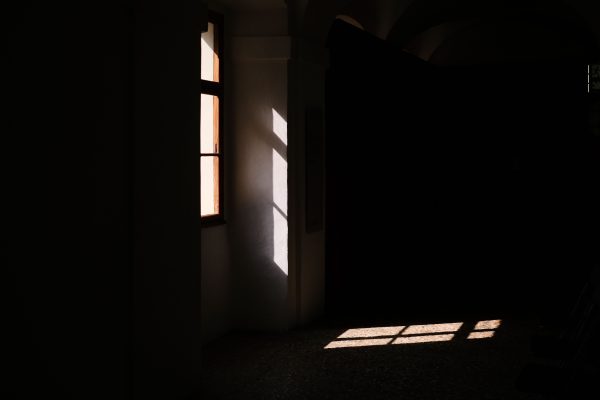 A dark room with sunlight streaming through a window, creating dramatic shadows. Dark 4K