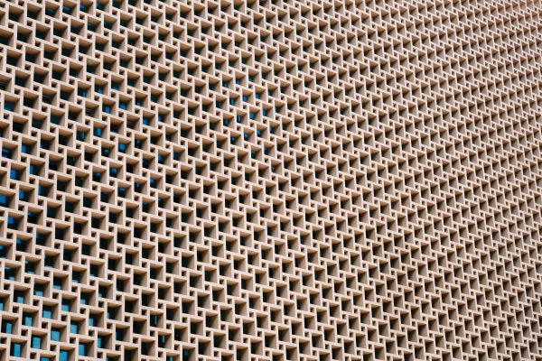 A detailed view of a geometric concrete wall with repetitive patterns and open spaces. Abstrait 4K