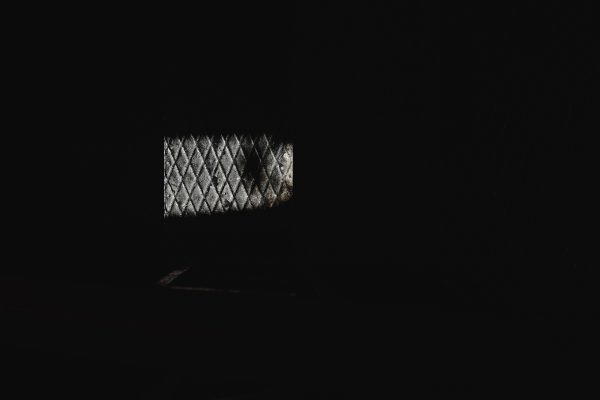 A dimly lit diamond-patterned window in a dark room, showcasing minimalist design and texture. Dark 4K