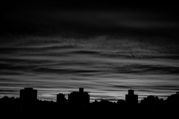 A dramatic black and white city skyline silhouette with a moody twilight sky. Architecture 4K