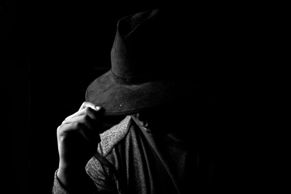 A dramatic black and white portrait of a person wearing a hat, creating a mysterious mood. Dark 4K