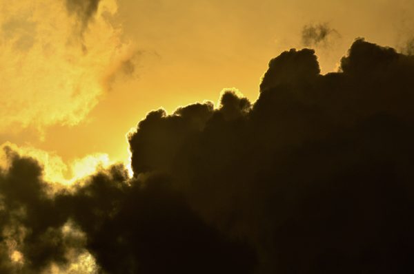 A dramatic scene of dark clouds outlined by the golden light of sunset, creating an awe-inspiring sky. Dark 4K