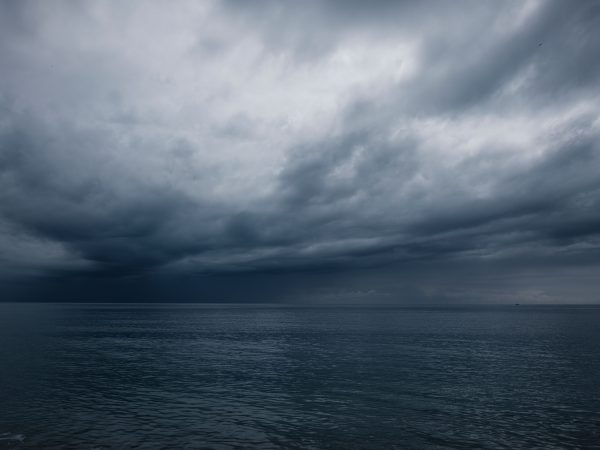 A dramatic seascape with dark clouds over a calm ocean at dusk, evoking a moody atmosphere. Nature 4K
