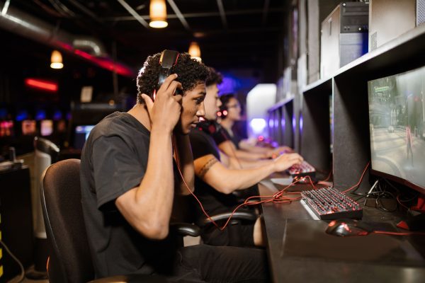 A group of young adults intensely focused on playing video games in a modern gaming lounge. Gaming 4K