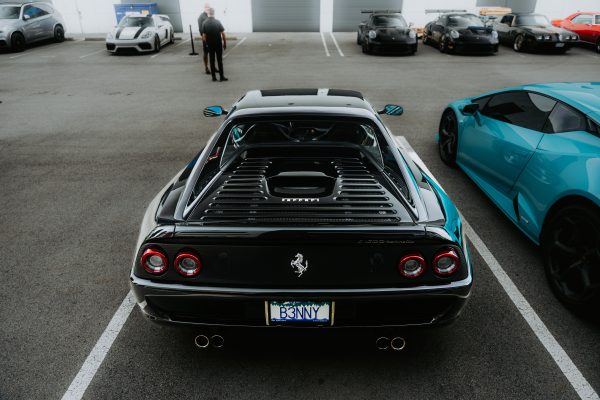 A high-end Ferrari parked among other luxury sports cars, showcasing automotive elegance in an open lot. Voitures 4K
