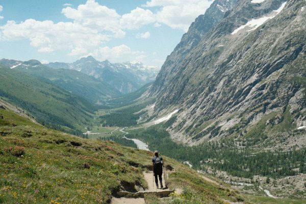 A lone hiker enjoying a scenic walk in a stunning alpine landscape during summer. Nature 4K