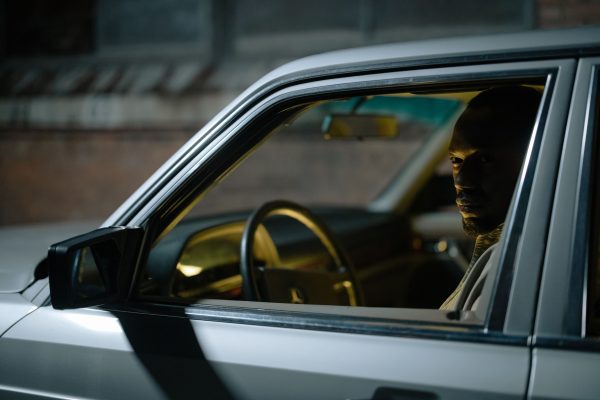 A man sitting inside a car at night, casting a mysterious and dramatic look. Voitures 4K