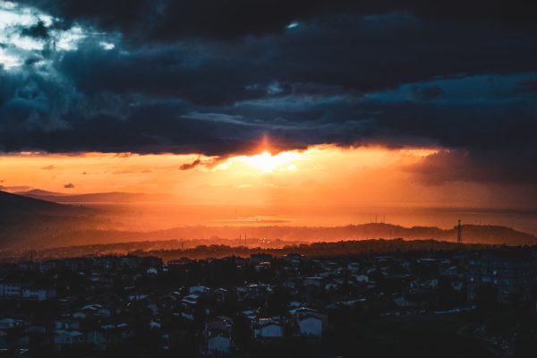 A mesmerizing sunset with dark clouds over a cityscape, capturing a mix of light and shadows. Dark 4K