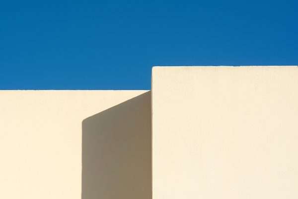 A minimalist architectural structure with white walls contrasting a vivid blue sky. Minimaliste 4K