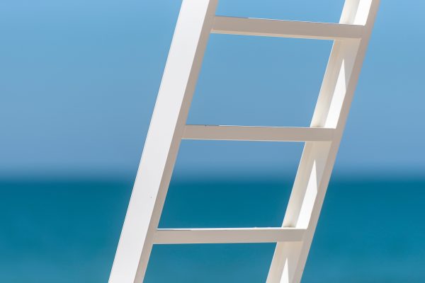 A minimalist image of a white ladder against a vibrant blue sea background, conveying peace and simplicity. Minimaliste 4K