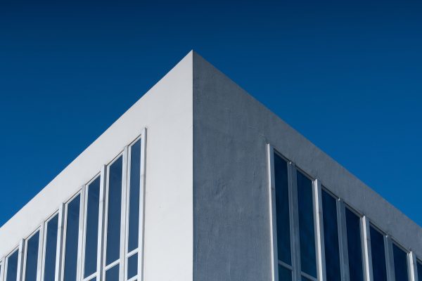 A modern building corner with large windows against a vibrant blue sky, showcasing minimalist architecture. Minimaliste 4K