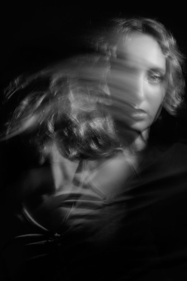 A moody black and white portrait of a woman with artistic motion blur effect. Mobile 4K