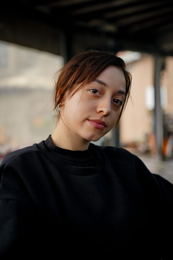 A natural light portrait of a young woman indoors with a neutral expression. Mobile 4K