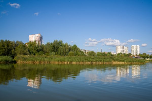 A peaceful riverside scene with urban buildings reflecting in the water on a sunny day. Nature 4K