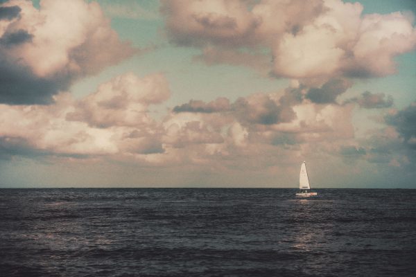 A peaceful seascape featuring a solitary sailboat under a dramatic sky in Cancun, Mexico. Nature 4K