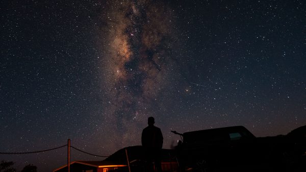 A person silhouetted against the stunning backdrop of the Milky Way and a starry night sky. Espace 4K
