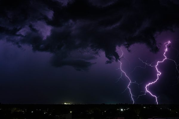 A powerful thunderstorm with dramatic lightning strikes over a city at night in India. Dark 4K