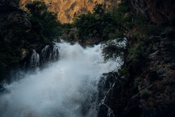 A powerful waterfall flows through a rocky landscape, surrounded by lush greenery. Nature 4K