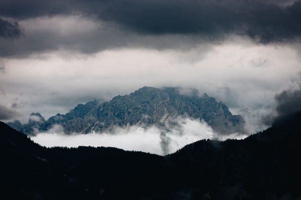 A scenic mountain peak partially obscured by clouds creates a dramatic natural landscape. Nature 4K