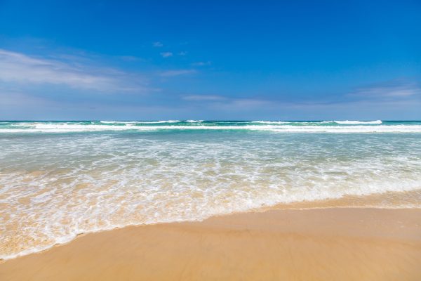 A serene beach with gentle waves and a clear blue sky, perfect for a summer day. Nature 4K