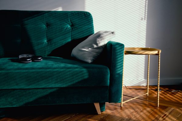 A serene living room featuring a sunlit green velvet sofa and modern minimal decor. Minimaliste 4K
