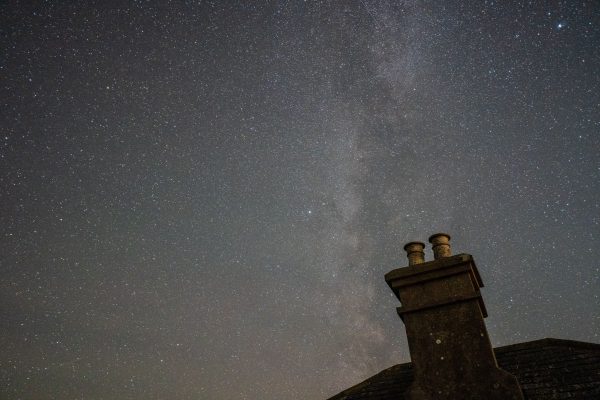 A serene night sky filled with stars, highlighting a silhouette of a rooftop chimney against the Milky Way. Espace 4K