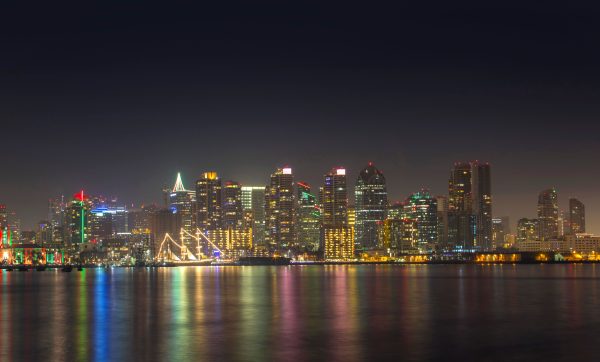 A serene night view of San Diego's illuminated skyline reflecting on calm water. Architecture 4K