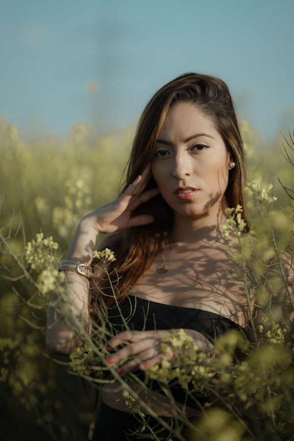 A serene portrait of a woman standing in a blooming meadow with yellow flowers in spring. Mobile 4K