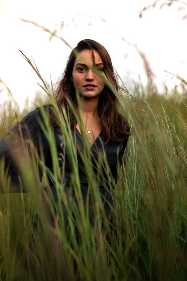 A serene portrait of a woman standing in a field of tall grass, exuding natural beauty and tranquility. Mobile 4K