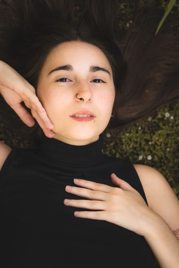 A serene portrait of a young woman lying on grass during the day, showcasing relaxation and tranquility. Mobile 4K
