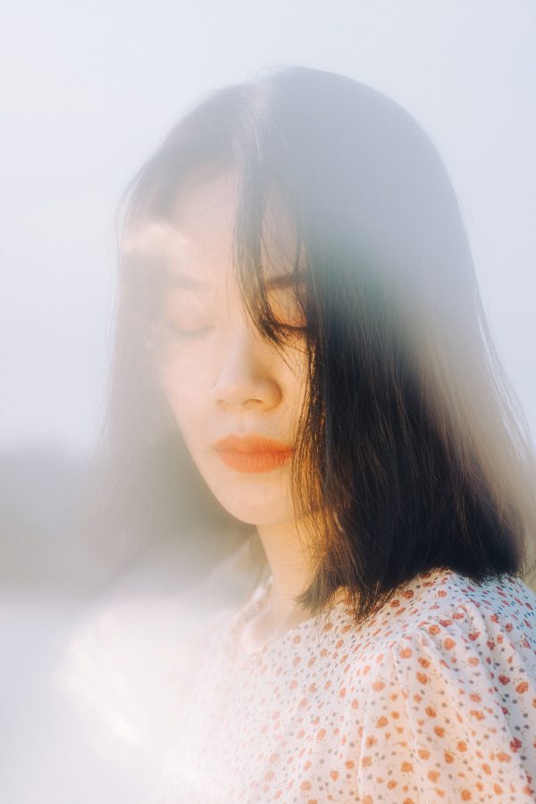 A serene portrait of an Asian woman with closed eyes, embracing a dreamy ambiance under natural light. Mobile 4K