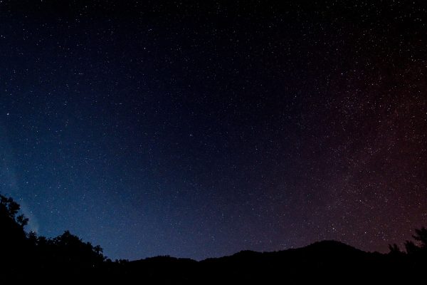 A serene view of a star-filled night sky over silhouettes of hills in Italy. Espace 4K