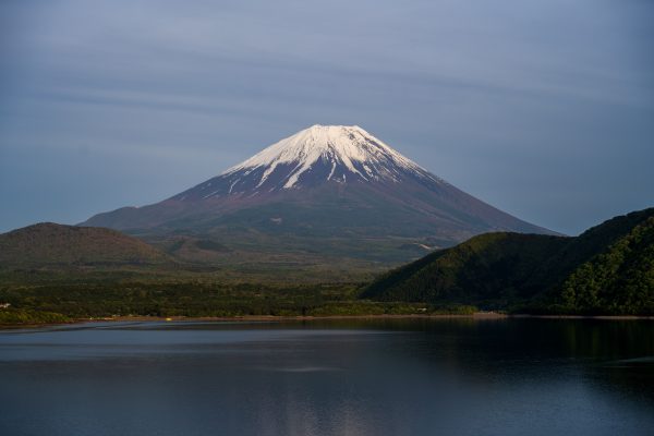 A serene view of Mount Fuji with snow-capped peak under a clear sky, reflecting in a tranquil lake. Anime 4K