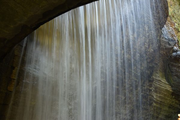 A serene waterfall cascading under a stone bridge in Cognola, Trentino-Alto Adige, Italy. Nature 4K