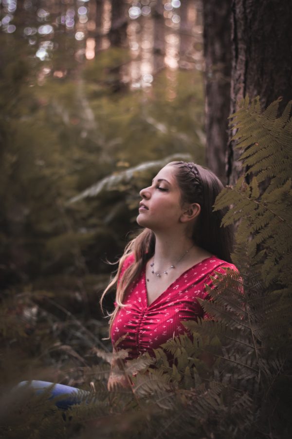 A serene woman in a red blouse enjoying nature in a forest setting. Mobile 4K