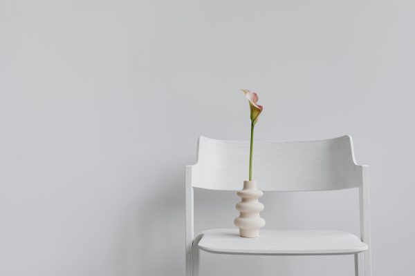 A single calla lily in a decorative vase atop a white chair, showcasing minimalist elegance. Minimaliste 4K