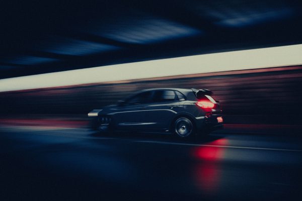 A sleek car speeds through a dimly lit tunnel, creating a dramatic motion blur effect. Voitures 4K